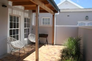 a patio with two chairs and a table at Botany House, in the heart of Hermanus in Hermanus