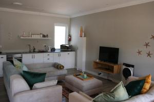 a living room with two couches and a television at Botany House, in the heart of Hermanus in Hermanus