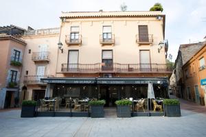 un ristorante con tavoli e sedie di fronte a un edificio di Apartament al cor de Begur a Begur