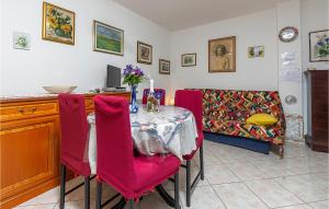 バーバリガにあるStunning Apartment In Barbariga With Wifiのダイニングルーム(テーブル、赤い椅子付)