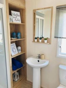 La salle de bains est pourvue d'un lavabo, d'un miroir et de toilettes. dans l'établissement The Wardens Hideaway - Tattershall Lakes Country Park, à Tattershall