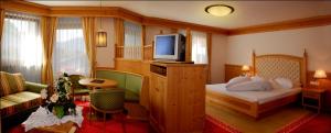 キウーザにあるNaturhotel Sonnenhofのベッドとテレビが備わるホテルルームです。
