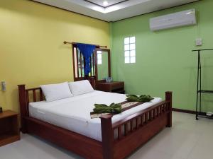 a bedroom with a bed with white sheets and green walls at Coconut corner in Ko Yao Noi