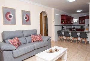 a living room with a gray couch and a kitchen at Apto ISA: amplio y acogedor apto de 75m con terraza, aire acondicionado y parking gratuito in Los Abrigos