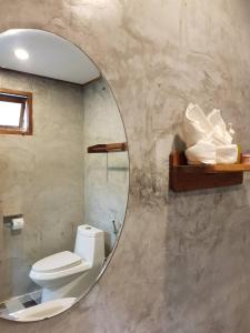 a bathroom with a toilet and a round mirror at Coconut corner in Ko Yao Noi