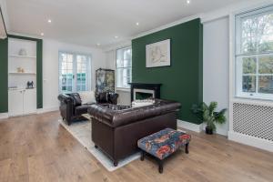 a living room with a leather couch and a fireplace at The London House - Entire Villa in London