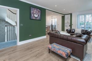 a living room with a brown leather couch and green walls at The London House - Entire Villa in London