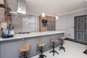 una cucina con bancone e sgabelli di The London House - Entire Villa a Londra