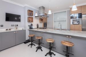 a kitchen with a counter and stools in it at The London House - Entire Villa in London