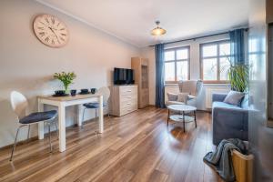 a living room with a table and chairs and a clock at Apartament Górna na 5 in Jelenia Góra