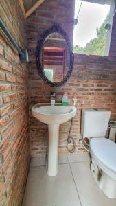 a bathroom with a sink and a mirror and a toilet at Cabana na Floresta Rincão do Fortaleza in Cambará