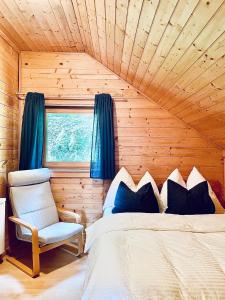 een slaapkamer met een bed, een stoel en een raam bij Blockhaus Semmering in Steinhaus am Semmering