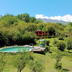 a swimming pool in a field with a house in the background at Los Lirios in Los Hornillos