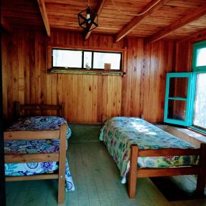 1 dormitorio con 2 camas en una cabaña de madera en Los Lirios en Los Hornillos