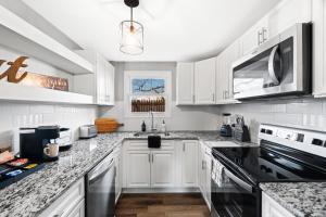 a white kitchen with white cabinets and black appliances at Lovely 3 Bedroom Colonial home in Middletown
