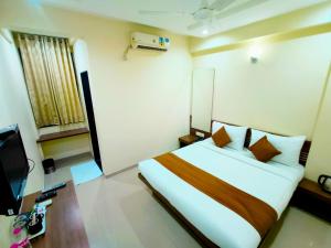 a hotel room with a bed and a television at SAI SRUSHTI by NEEM SQUARE in Shirdi