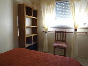 1 dormitorio con 1 cama, 1 silla y 1 ventana en Dpto 2 AMB cerca de la playa en Santa Teresita en Santa Teresita
