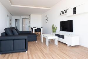 uma sala de estar com um sofá preto e uma televisão em 3 bdr aprt, best seaview, rooftop pool - LCGR em Praia