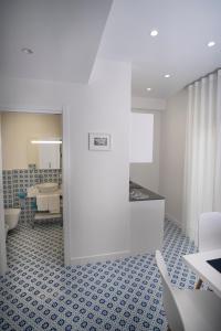 uma casa de banho com uma parede branca e piso em azulejo azul em Domus Sole em Sorrento