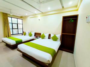 two beds in a room with green and white at SAI SRUSHTI by NEEM SQUARE in Shirdi