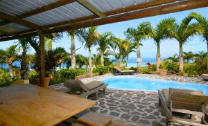 un patio con mesa y sillas y una piscina en Fenetre sur Mer, en Rodrigues Island