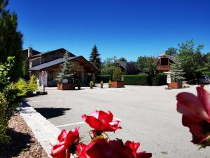 a parking lot with red flowers in front of a building at PRL Le Védrignans - PRL El Pastural in Saillagouse