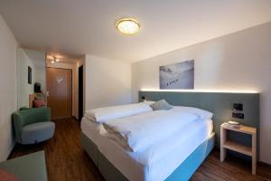 1 dormitorio con 1 cama blanca grande y 1 silla en Sport-Lodge Klosters, en Klosters