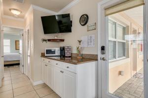 a kitchen with a counter with a tv on the wall at Walkable to Restaurants and Steps to the Beach! - Coconut Villa's Suite 10 in St. Pete Beach