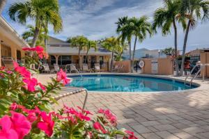 a swimming pool with palm trees and pink flowers at Walkable to Restaurants and Steps to the Beach! - Coconut Villa's Suite 10 in St Pete Beach