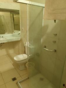 a bathroom with a toilet and a glass shower at Hotel Bragança in Caxambu +129 photos