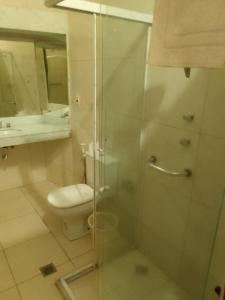 a bathroom with a toilet and a glass shower at Hotel Bragança in Caxambu