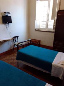 a bedroom with a bed and a chair and a window at Hotel Bragança in Caxambu