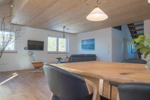 a dining room and living room with a wooden table and chairs at Haus Wiesenquelle, Deluxe-Apartment 'Feld & Berg' in Feldberg