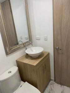 ein Badezimmer mit einem Waschbecken, einem WC und einem Spiegel in der Unterkunft Espectacular apartamento amplio y moderno a solo 20 min de termales in Manizales