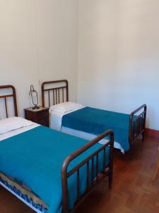 two beds in a room with blue sheets at Hotel Bragança in Caxambu