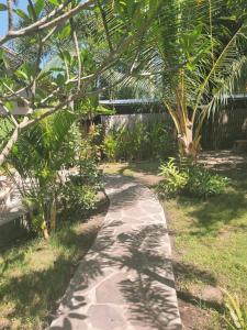ein Steinweg in einem Garten mit einer Palme in der Unterkunft Gili Matiki, Resort & Private Villa in Gili Air