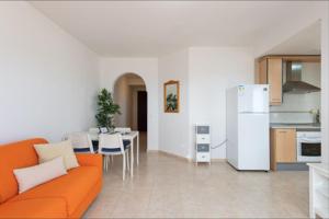 een woonkamer met een oranje bank en een keuken bij Fuerteventura Apartamento Costa Calma, Jandia in Costa Calma