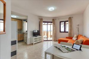 een woonkamer met een oranje bank en een keuken bij Fuerteventura Apartamento Costa Calma, Jandia in Costa Calma