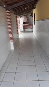 an empty hallway with white tile floors and a brick wall at Casa de praia em ponta de areia - Raio do Sol House in Itaparica Town