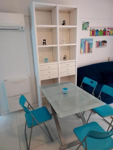 a dining room with a glass table and blue chairs at SOLARE in Bibione +15 photos