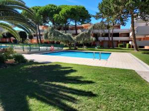 a swimming pool in a park with trees and a building at SOLARE in Bibione