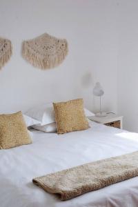 Una cama blanca con almohadas y una manta. en Sweet & Simple Beach Cottage, en Jeffreys Bay