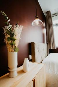 um vaso com flores numa mesa ao lado de uma cama em Sweet Love Room - Jacuzzi Privatif em Montreuil