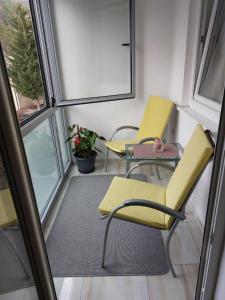 2 chaises et une table dans une chambre avec fenêtres dans l'établissement Apartment YESA, à Travnik