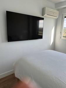1 dormitorio con 1 cama blanca y TV de pantalla plana en Apartamento cerca centro Madrid en Rivas-Vaciamadrid
