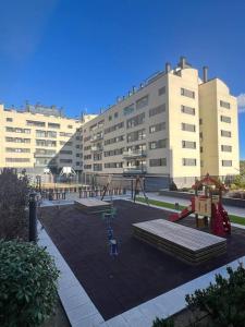 een lege speeltuin voor een groot gebouw bij Apartamento cerca centro Madrid in Rivas-Vaciamadrid