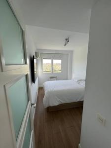 um quarto branco com uma cama e uma janela em Apartamento cerca centro Madrid em Rivas-Vaciamadrid