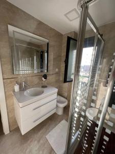 een badkamer met een wastafel, een toilet en een spiegel bij Apartamento cerca centro Madrid in Rivas-Vaciamadrid