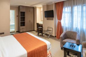 a hotel room with a bed and a chair and a tv at Hotel Waterbuck in Nakuru