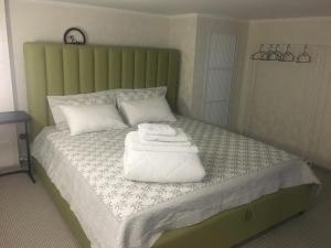 a bed with a green headboard with towels on it at Современные и уютные аппартаменты in Borovoye
